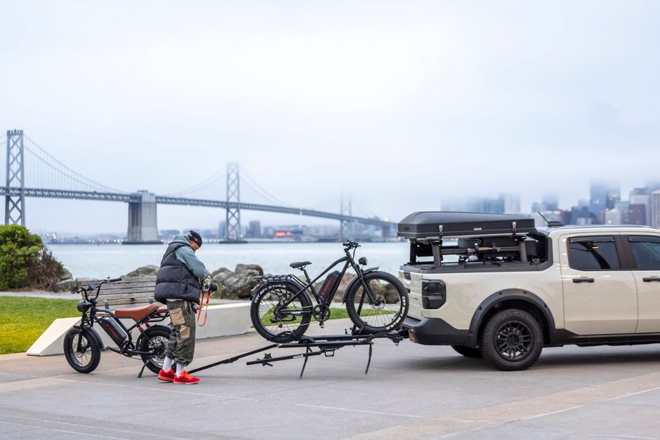 A cyclist prepares e-bikes on a carrier near San Francisco's Bay Bridge.