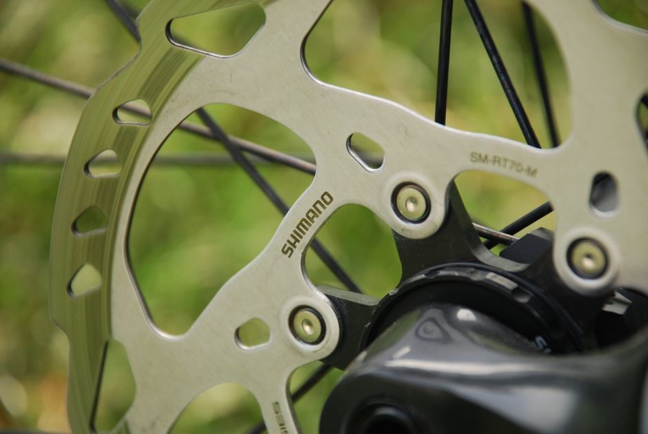Detailed shot of a Shimano disc brake and wheel spindle on a bicycle.